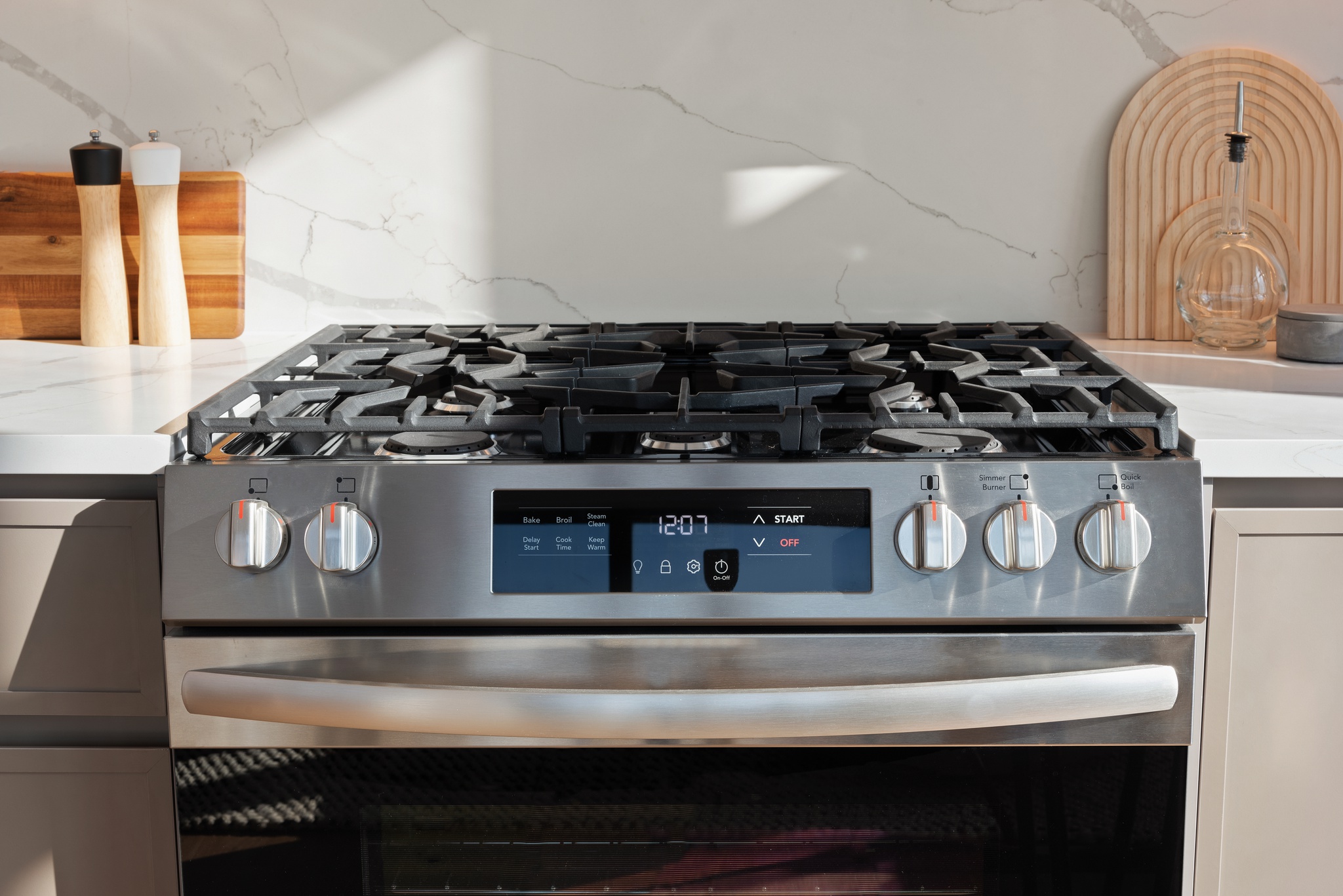 Detail of stainless steel stove/oven and white marble looking backsplash and counter