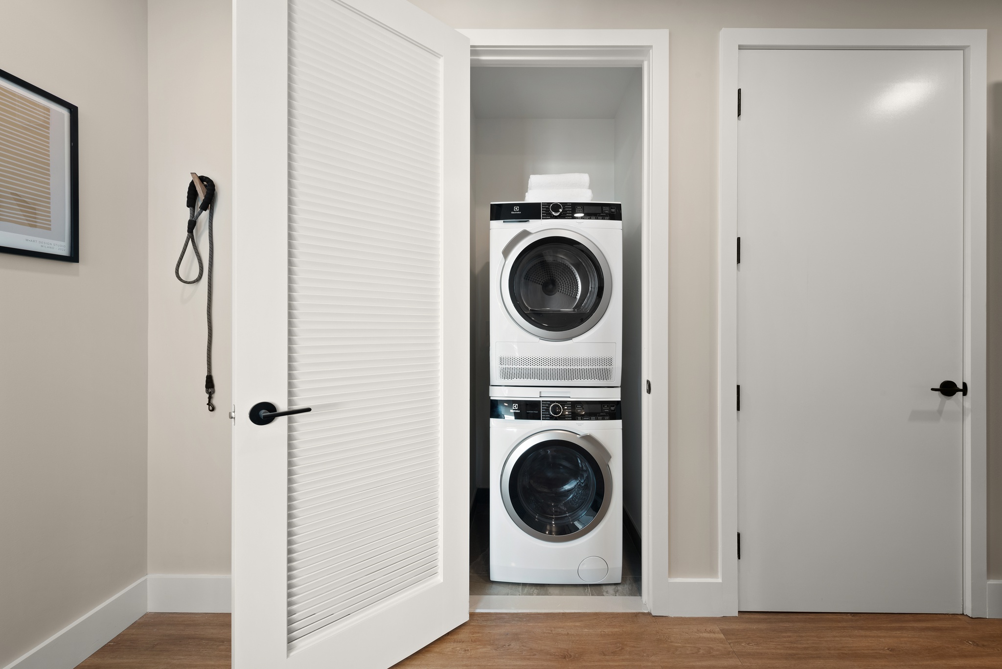 washer dryer combo in closeted area with white doors, wood floors and light colored walls with white molding